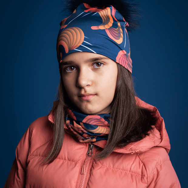 Young girl in front, wearing the Sound Barrier designed by Zaire with a navy pom-pom. The bamboo beanie is perfect for outdoor activities and camping. Best snowboarding and ski beanie. Perfect gift for the whole family