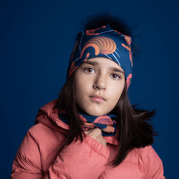 Young girl in front, wearing the Sound Barrier maid designed by Zaire with a navy blue pom-pom. The bamboo cap is perfect for outdoor activities.